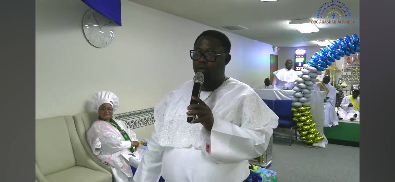 VSE Michael Akin Akinmaye, dressed in white garments, ministering with a microphone during a service at CCC Agashadua Parish